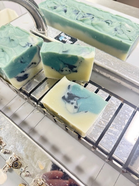 Handmade soap bars with blue and green swirls on a metal rack.